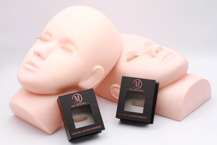 Two mannequin heads with Ultra Real Lash Practice Eyelids used as realistic lash training tool
